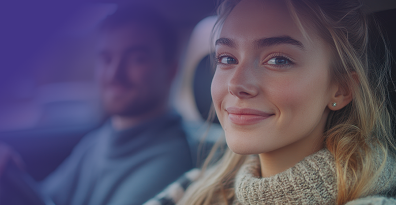 lächelnde Fahrschülerin sitzt im Auto am Lenkrad