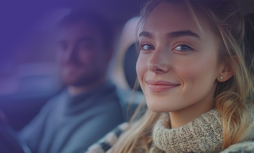 lächelnde Fahrschülerin sitzt im Auto am Lenkrad